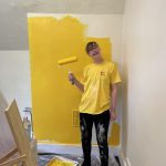 Sophie smiles while painting at ESTEEM with a roller brush