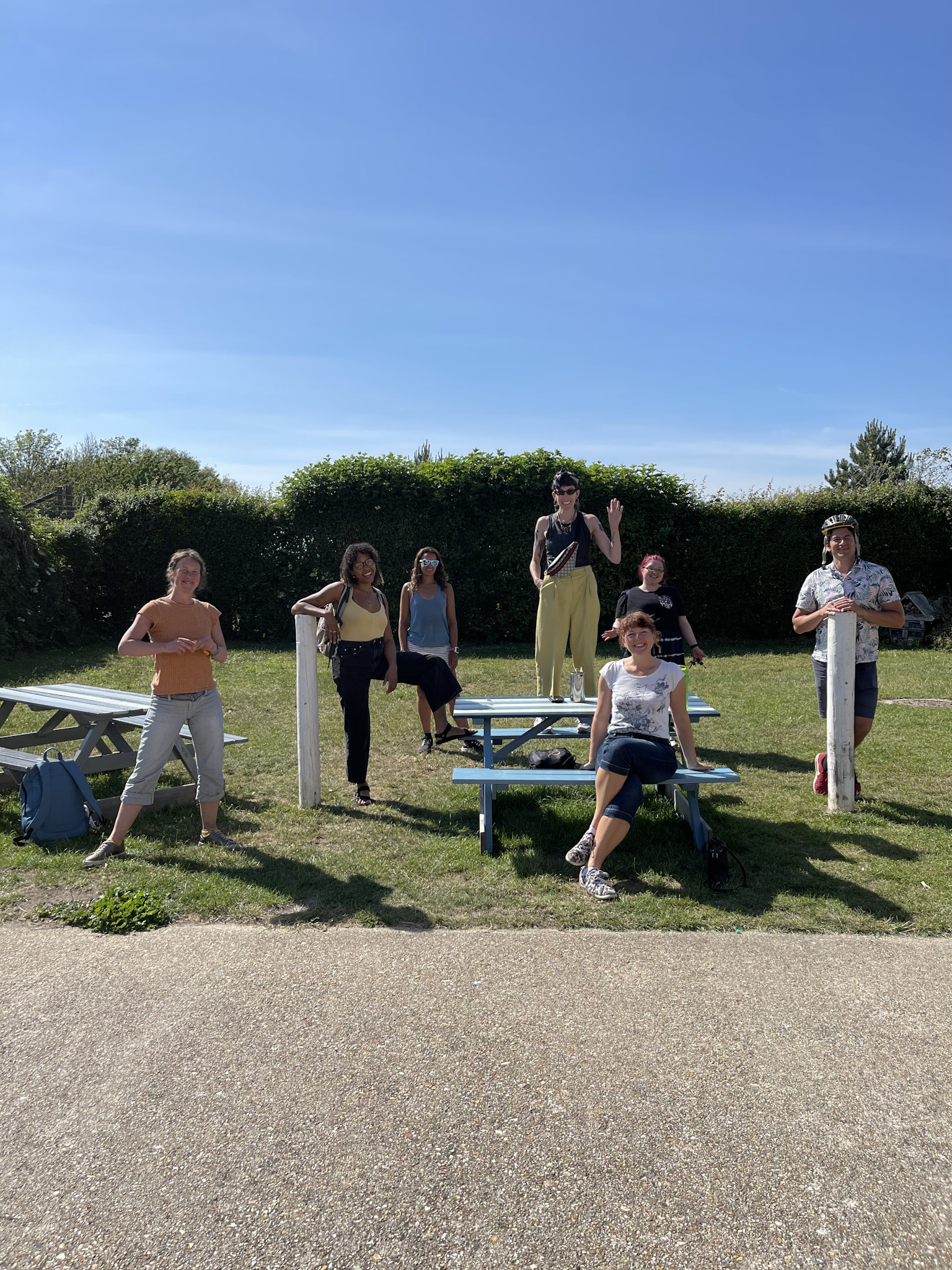 A number of staff pose in different funny positions. One is standing on a table.