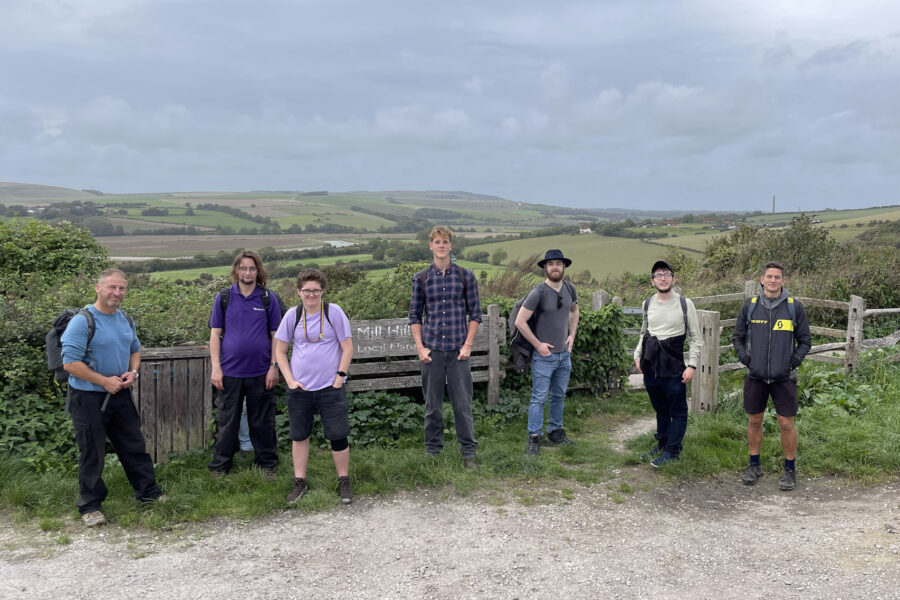 Young adults and staff lined up against the backdrop of hills and nature